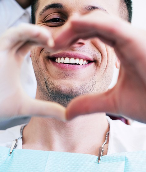 Patient and dentist making a heart with their hands