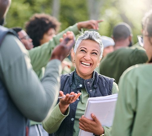 Woman with clipboard smiling at group outside