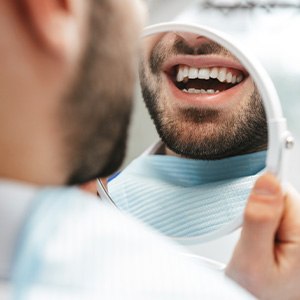 Patient smiling at reflection in handheld mirror