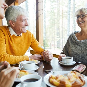 Group of adults smiling while eating lunch outside