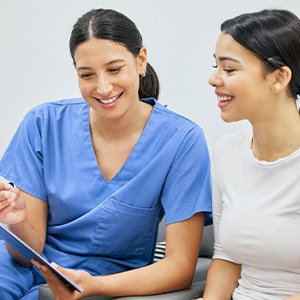 Dental assistant showing patient forms on clipboard