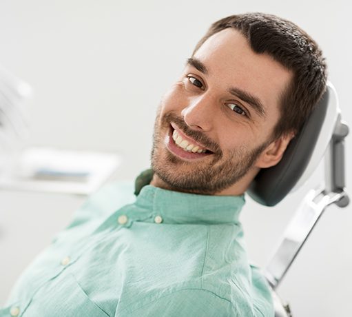 A smiling man sitting in a dentist’s chair