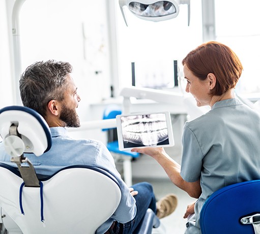 Smiling dental assistant and patient looking at X-ray