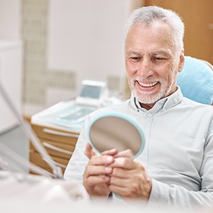 Man smiling at reflection in handheld mirror