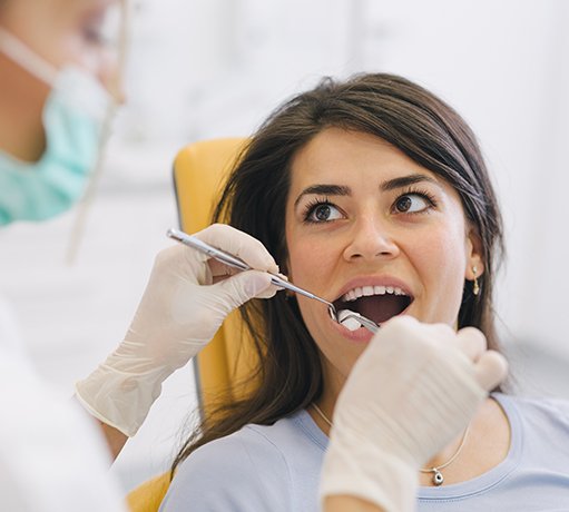 Woman with brown hair looking at dentist during oral examination